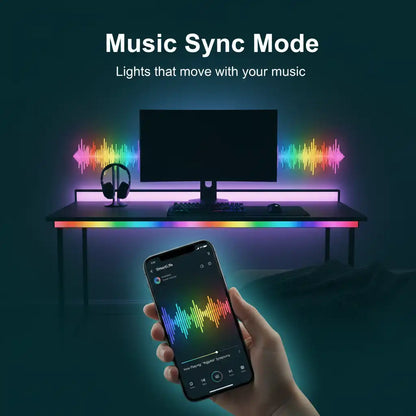 A hand holds a smartphone showing a music app with colorful LED soundwave graphics, while a desk setup in the background glows with rainbow RGB lighting. Text at the top reads 'Music Sync Mode' and 'Lights that move with your music.